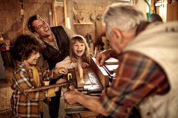 Fototapeta premium Happy multigenerational family woodworking together in workshop
