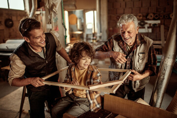 Three generations of men bonding in woodworking workshop