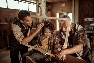Three generations of men bonding in woodworking workshop