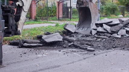 Heavy machinery is breaking up asphalt on a roadway for essential repairs and maintenance work for safety