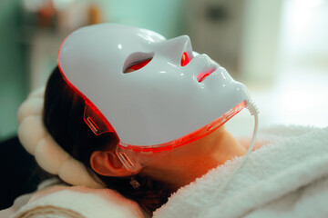 Woman Getting Red Light Therapy for her Skin with Mask. Lady using professional services in a...