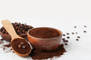 Spoon with bowls of coffee powder and beans on white background, closeup