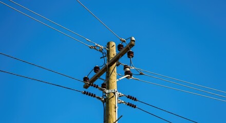 Wooden utility pole with electrical wires against clear blue sky