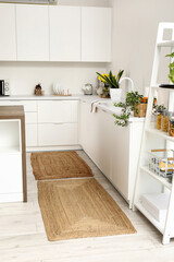 Wicker rugs on floor in interior of light kitchen