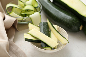Bowls with slices of fresh zucchini on white background