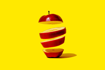 Red apple slices floating against a vibrant yellow background