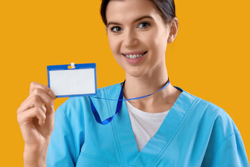 Female medical intern with badge on yellow background, closeup