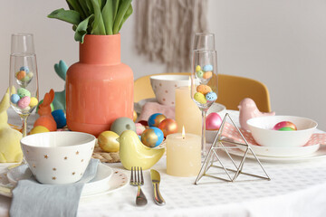 Stylish table setting with vase, candles and painted eggs
