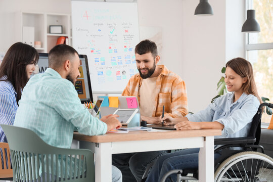 Team of designers with woman in wheelchair working at office