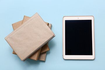 Books with modern tablet computer on blue background. Concept of evolution