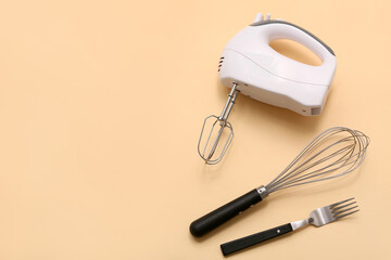 Modern mixer with whisk and fork on beige background. Concept of evolution