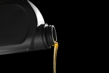 Pouring of machine oil from bottle on black background, closeup