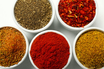 Bowls with different aromatic spices on white background, closeup
