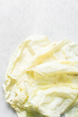 Overhead view of cabbage leaves on a marble countertop, top view of green and yellow cabbage leaves