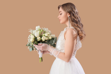 Beautiful bride in white wedding dress with flowers on beige background