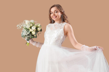Beautiful bride in white wedding dress with flowers on beige background