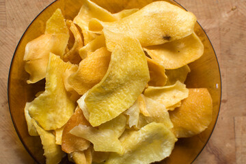 Overhead view of golden sweet potato chips on wood countertop, top view of crispy fried sweet...