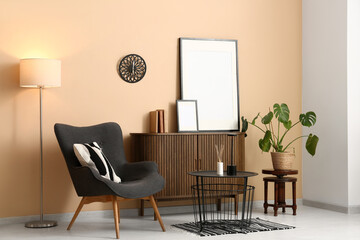 Armchair with wooden commode, glowing lamp and black table in living room