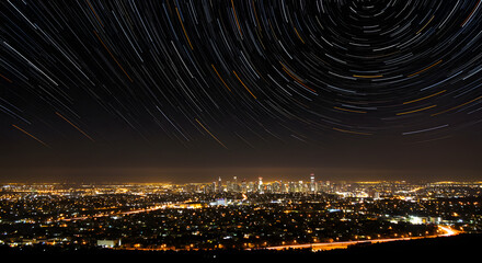 A sprawling cityscape glows beneath a dark, starry sky, captured from a distant hilltop.