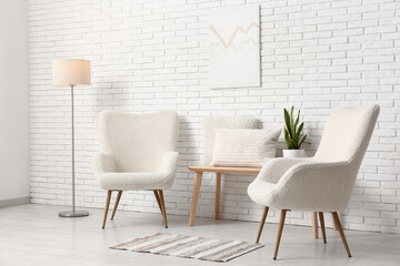 White armchairs with floor lamp, bench and pillows in light room