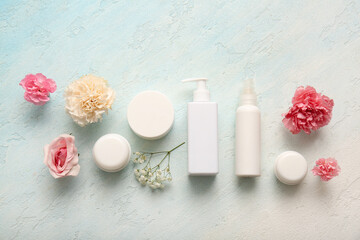 Different cosmetics and beautiful flowers on light background