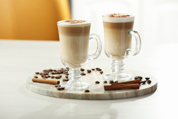 Tasty latte macchiato, coffee beans and cinnamon sticks on white table, closeup