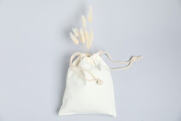 Cotton bag with dry spikes on light background, top view