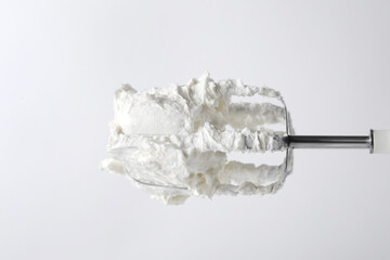 Whisk with whipped cream on white background, closeup