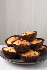 Delicious muffin with chocolate chips on light grey table, closeup