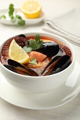 Delicious seafood soup in bowl on light wooden table, closeup