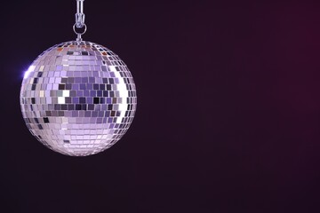 Shiny disco ball on dark purple background, space for text