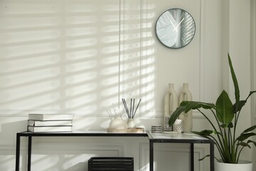 Console table with different decor near white wall indoors. Interior design