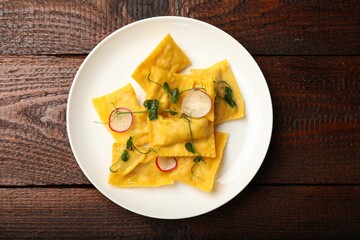 Delicious ravioli with microgreens and radish on wooden table, top view