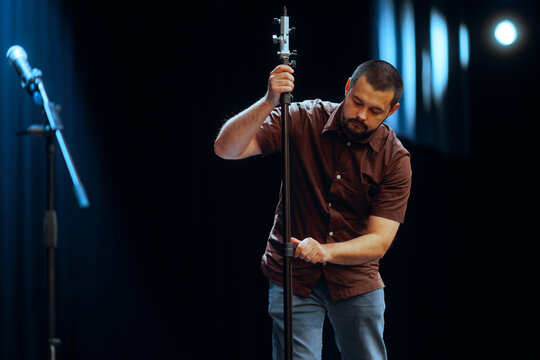 Technician Adjusts and Arranges a Microphone on Stage. Man getting reading before a concert setting up the audio equipment 
