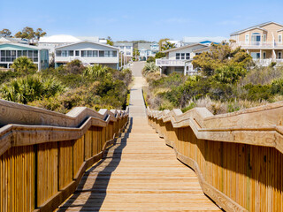Long wood bridge leading to beach houses on the East Coast during a sunny day with beautiful blue...