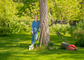 portrait of a woman with a rake and a lawn mower