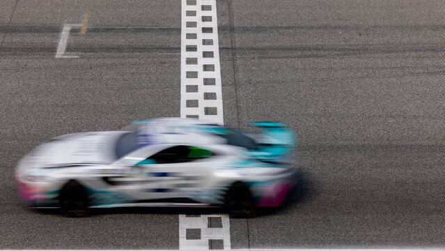 Fototapeta Motion blurred super car crossing finish line checkered on race track circuit, Race super car blurred motion crossing finish checkered line on race track, concept win and goal reached.