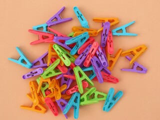 Multicolored plastic clothes peg on orange background.