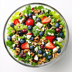 Vibrant salad in a clear glass bowl, showcasing a colorful mix of fresh greens, strawberries, blueberries, and walnuts