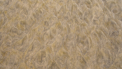 Intricate sand ripples shaped by natural elements, forming an abstract and artistic texture on the beach.