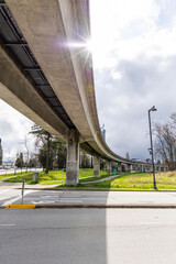 Fototapeta premium Concrete Elevated Transit Overpass in Surrey with Sun Glare and Green Surroundings