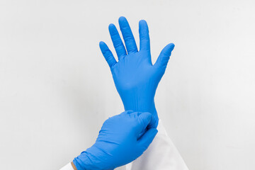 Woman doctor putting blue latex medical gloves on white background.Surgeon wearing gloves before surgery at operating room.Risk and infection control concept