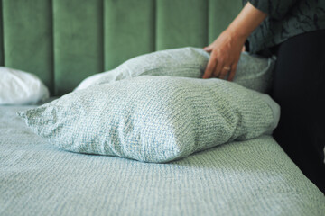 Pillows being arranged on a neatly made bed in a cozy room