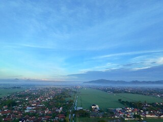 Aerial photography of rural settlement rice field scenery, sunrise in the morning with beautiful dew mist