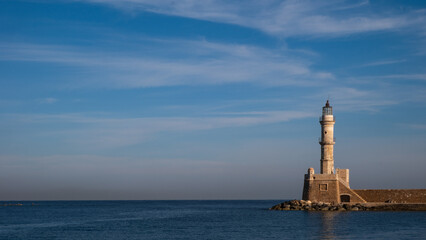 Entrance to the harbor at Chania, Crete, with the historic stone lighthouse and the blue Aegean Sea