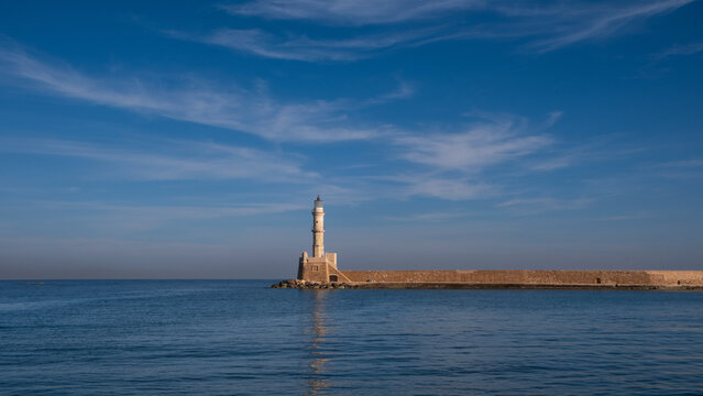 The historic lighthouse marking the entrance to the harbor at Chania in Crete, Greece with blue skies and wispy clouds - Powered by Adobe