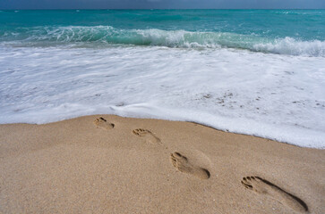 Foot steps on sand. Tropical coastline. Exotic sea beach destination. Foamy sea beach waves. Sunny sea beach holiday. Relaxing sea beach vacation.