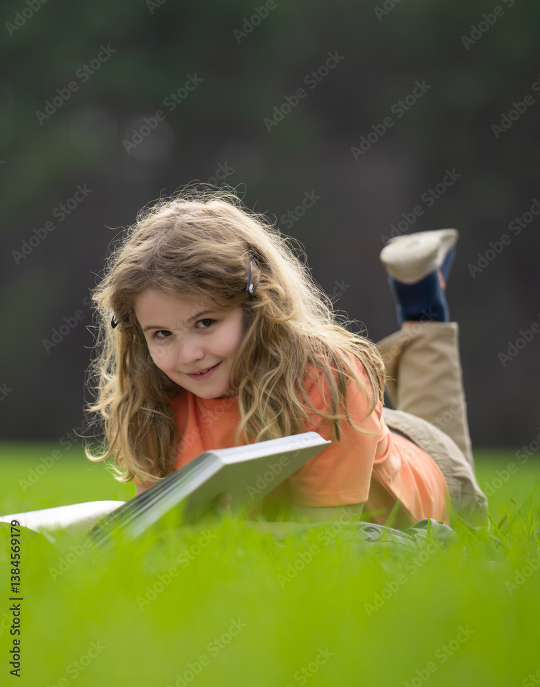 Poster child reading a book in the grass. kid enjoying a book story outdoors. child studying with book in t