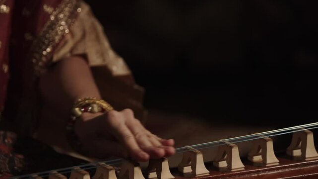 A close-up of hands skillfully playing a traditional Thai musical instrument called the 'chakhe'.
