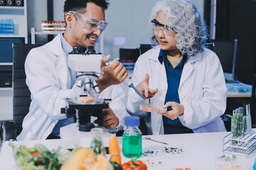 Team Asian scientists in a lab conducting food research using a microscope and lab equipment,...